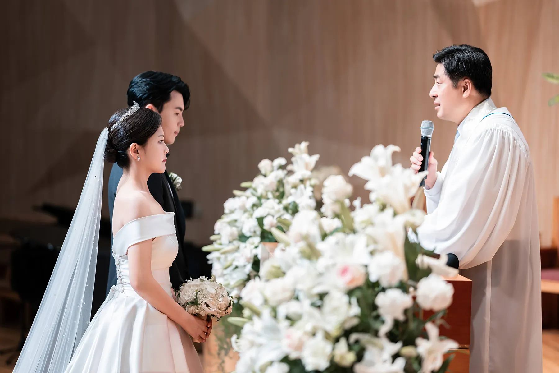 꽃장식 너머 마주 선 신랑신부를 담은 혼인예배 본식영상 촬영 장면